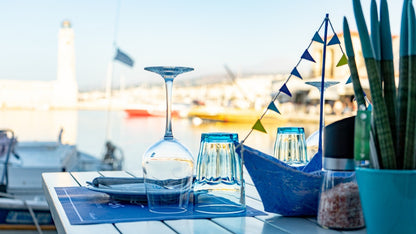 Gedeckter Tisch in einem Hafenrestaurant mit Leuchtturm im Hintergrund